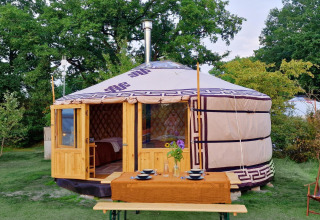 Una yurta mongola con entrada de madera, mesa preparada y naturaleza verde en Zomerlicht, Países Bajos.