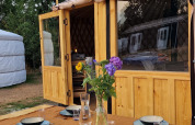 Udendørs spisebord med service foran en Mongoolsk Panorama Yurt ved Zomerlicht i Holland, omgivet af natur.