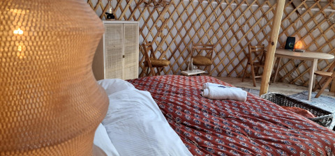 Innenraum einer mongolischen Panorama-Yurte bei Zomerlicht, Niederlande, mit Bett und gemütlicher Einrichtung.