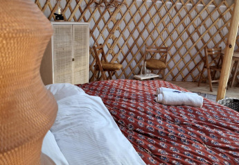 Intérieur de la Mongoolse Panorama Yurt à Zomerlicht, Pays-Bas, avec lit et décoration rustique chaleureuse.