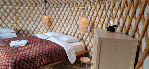 Gemütliche Inneneinrichtung einer Mongolischen Panorama-Yurt bei Zomerlicht, Niederlande, mit Bett.