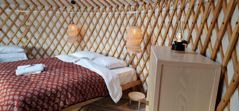 Cozy interior of the Mongoolse Panorama Yurt at Zomerlicht, Netherlands, featuring bed and wood decor.