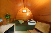 Wooden interior of Duo pød at RØSTIG Dorst, Netherlands, with bed, chair, small window and flowers.
