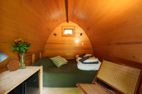 Intérieur bois du Duo pød à RØSTIG Dorst, Pays-Bas, avec lit, chaise, petite fenêtre et fleurs.