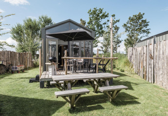 Rescue cottage lodge at Duynpark Het Zwanenwater, Netherlands, with wooden deck, picnic table and fenced yard.