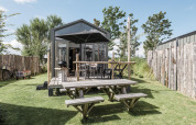 Rescue cottage lodge at Duynpark Het Zwanenwater, Netherlands, with wooden deck, picnic table and fenced yard.