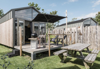 Vue extérieure du Rescue cottage à Duynpark Het Zwanenwater, avec terrasse, parasol et table de pique-nique.