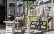 Outdoor terrace at Rescue cottage in Duynpark Het Zwanenwater, Netherlands, with grill, chairs and table.
