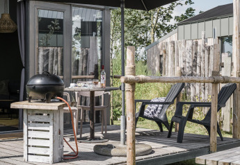 Outdoor terrace at Rescue cottage in Duynpark Het Zwanenwater, Netherlands, with grill, chairs and table.