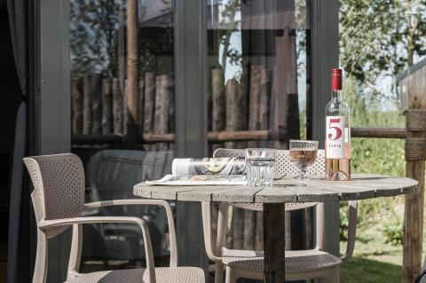 Terrassentisch mit Wein und Gläsern am Rescue Cottage, Duynpark Het Zwanenwater, Niederlande.