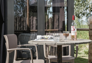 Terrassentisch mit Wein und Gläsern am Rescue Cottage, Duynpark Het Zwanenwater, Niederlande.