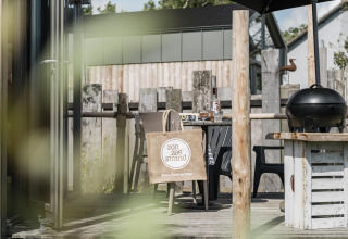 Outdoor deck at Rescue cottage, Duynpark Het Zwanenwater, Netherlands, featuring a grill, chairs, and tote bag.