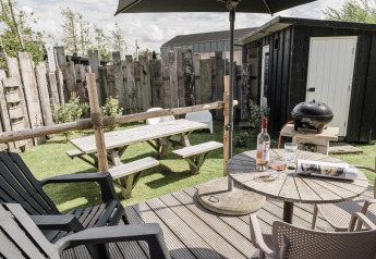 Tuin met picknicktafel, barbecue en wijn bij Rescue cottage, Duynpark Het Zwanenwater, Nederland.