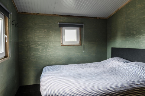 Schlafzimmer im Rescue Cottage in Duynpark Het Zwanenwater, Niederlande, mit schlichter Einrichtung.