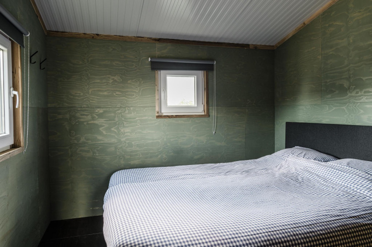 Dormitorio en Rescue cottage de Duynpark Het Zwanenwater, Países Bajos, con decoración sencilla y ropa de cama a cuadros.