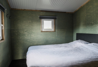 Slaapkamer in Rescue cottage bij Duynpark Het Zwanenwater, Nederland, met eenvoudige inrichting en geruite dekens.