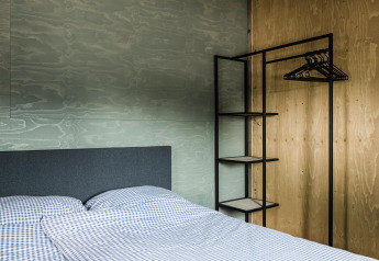 Dormitorio moderno en Rescue Cottage, Duynpark Het Zwanenwater, Países Bajos, con cama y guardarropa abierto.