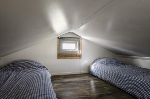 Dos camas individuales con ropa de cama a cuadros en una buhardilla del Rescue cottage, Duynpark Het Zwanenwater.