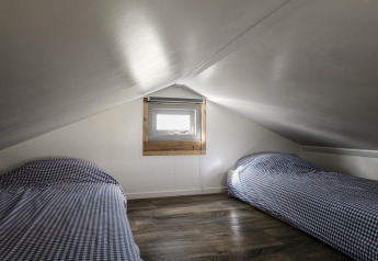 Dos camas individuales con ropa de cama a cuadros en una buhardilla del Rescue cottage, Duynpark Het Zwanenwater.