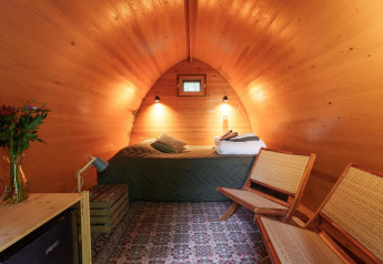 Vista interna del Duo Pod Large al RØSTIG Dorst nei Paesi Bassi con letto, sedie e pareti in legno.
