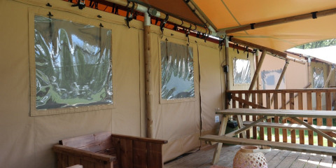 Tienda de safari Luxury Lodge con terraza de madera y banco en Holiday park De Kleine Belties, Países Bajos.