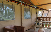 Tienda de safari Luxury Lodge con terraza de madera y banco en Holiday park De Kleine Belties, Países Bajos.