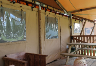 Tienda de safari Luxury Lodge con terraza de madera y banco en Holiday park De Kleine Belties, Países Bajos.