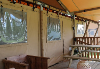 Luxueuze Lodge Safari Tent met houten terras en picknickbank bij Holiday park De Kleine Belties in Nederland.
