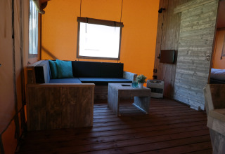 Interior de una tienda safari de lujo en Holiday park De Kleine Belties, Países Bajos, con muebles rústicos.