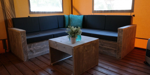 Zona living interna nella Luxury Lodge Safari Tent con mobili in legno al De Kleine Belties nei Paesi Bassi.