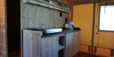 Coin cuisine dans une tente safari lodge de luxe avec meubles en bois et cafetière à De Kleine Belties.