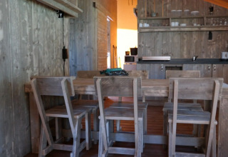Vista interior de la tienda safari Luxury Lodge con mesa de madera y cocina en De Kleine Belties, Países Bajos.
