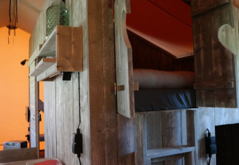 Interno di una tenda safari di lusso con letto a castello rustico in legno in un parco vacanze nei Paesi Bassi.