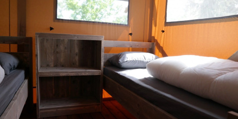 Interieur van een luxe safaritent met houten bedden bij Vakantiepark De Kleine Belties, Nederland.