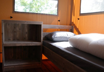 Interior of a luxury safari tent featuring wooden beds and shelf at Holiday Park De Kleine Belties, Netherlands.