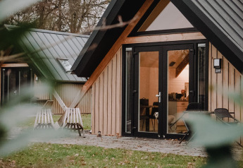 Vista esterna della tiny house Wellness Lodge al Holiday Park De IJsvogel, Paesi Bassi, immersa nel verde.