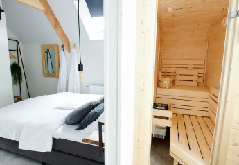 Bedroom with a double bed and wooden sauna at Wellness Lodge, Holiday Park De IJsvogel in the Netherlands.