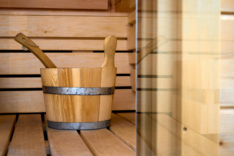Interieur van een traditionele sauna met houten banken, emmer en lepel in Wellness Lodge, De IJsvogel.