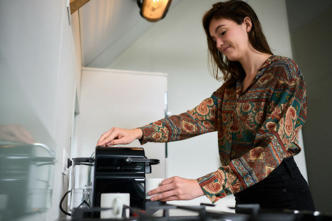 Donna che prepara il caffè nella tiny house Wellness Lodge al Holiday Park De IJsvogel, Paesi Bassi, cucina moderna.