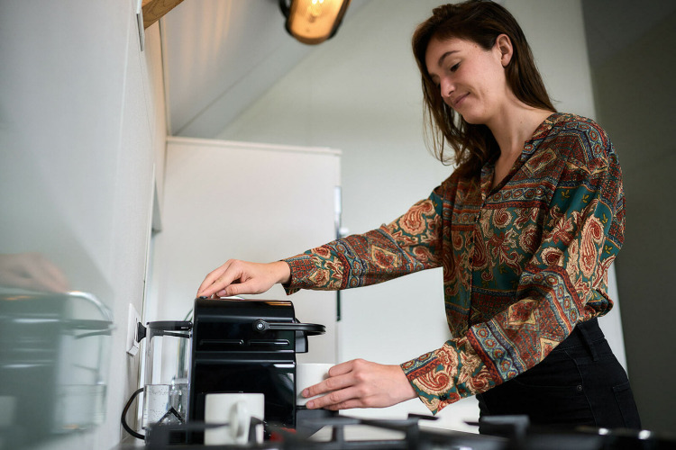 Mujer preparando café en la tiny house Wellness Lodge del Holiday Park De IJsvogel, Países Bajos, cocina moderna.