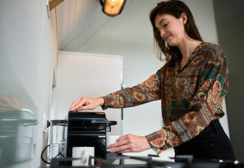 Mujer preparando café en la tiny house Wellness Lodge del Holiday Park De IJsvogel, Países Bajos, cocina moderna.
