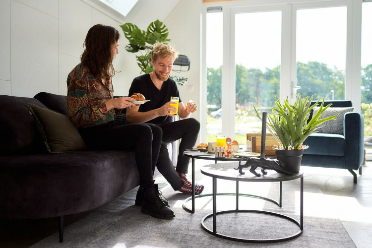 Dos personas desayunan en Wellness Lodge del Holiday Park De IJsvogel, Países Bajos, con luz natural en la sala.