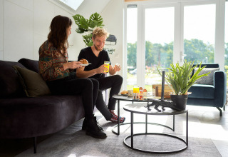 Dos personas desayunan en Wellness Lodge del Holiday Park De IJsvogel, Países Bajos, con luz natural en la sala.