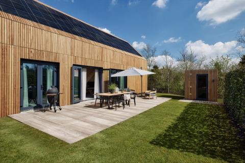 Modern lodge with wooden facade, solar panels, terrace, grill, and sauna at Brinckerduyn, Netherlands.