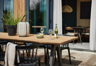 Buitentafel bij Unbrick One | Sauna bij Brinckerduyn, Nederland, gedekt met wijn, glazen en planten.