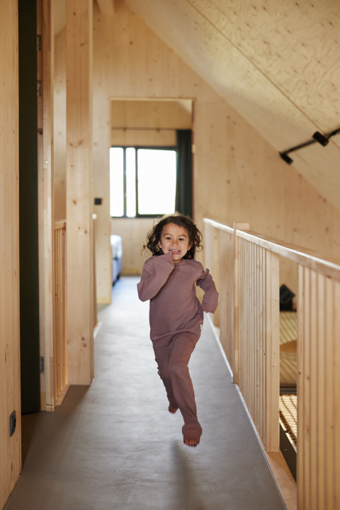 Un niño corre descalzo por un pasillo de madera en Unbrick One | Sauna at Brinckerduyn, Países Bajos.