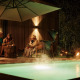 Drei Personen entspannen sich abends an einem beleuchteten Pool bei Unbrick One | Sauna und Pool in Brinckerduyn, Niederlande.