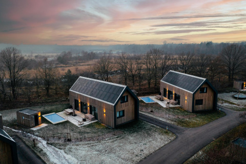 Moderne Lodges mit Sauna und Pool bei Sonnenuntergang im Brinckerduyn, Unbrick One, Niederlande.