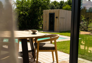 Terrazza esterna con tavolo e sedie in legno, vista su piscina e sauna a Unbrick One a Brinckerduyn, Paesi Bassi.