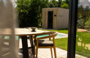 Outdoor terrace with wooden table and chairs, view of pool and sauna at Unbrick One in Brinckerduyn, Netherlands.